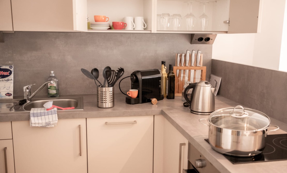 Apartmentküche mit Herd, Kaffeemaschine und kompletter Ausstattung